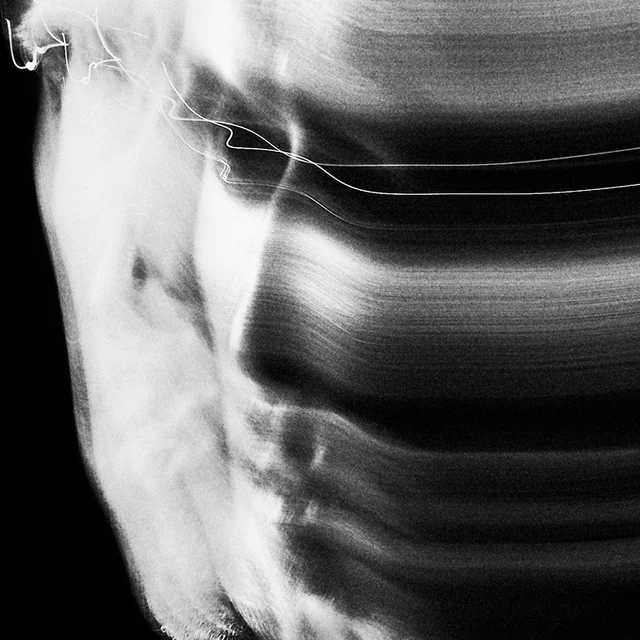 TRSSX in a monochrome long-exposure portrait, with a facial profile beside blurred light trails. Photography: Christopher Espinosa Fernandez. Archival print treatment.
