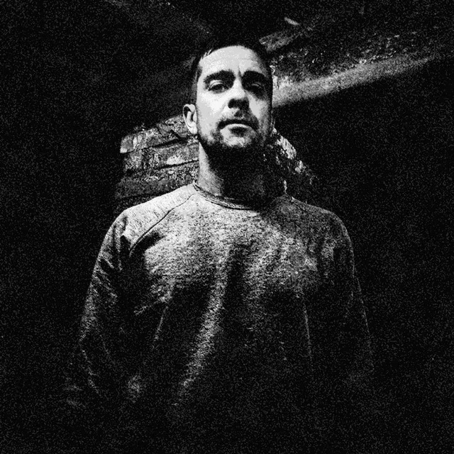 Elmer Davy in a sweatshirt in an industrial brick interior. Black-and-white photocopy-style print treatment.