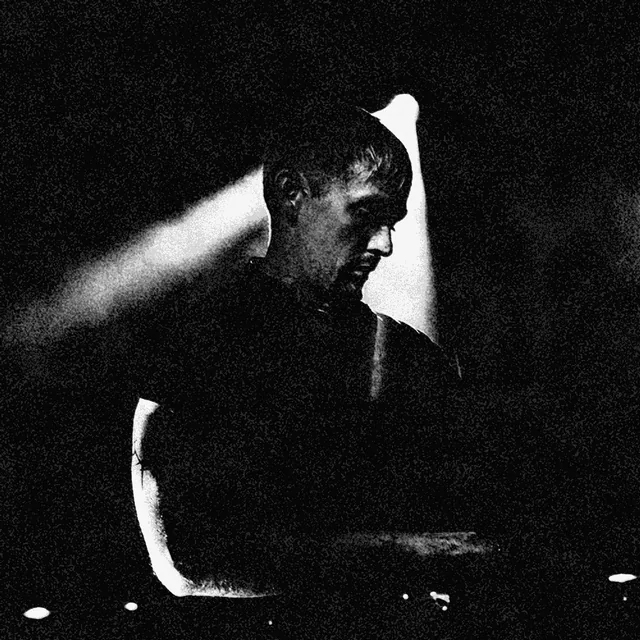 Swarm Intelligence performing with electronic equipment at Askorn Records, Brest, in 2022, with a tattooed forearm visible. Photography: Alix Mateuc’h. Black-and-white photocopy-style print treatment.