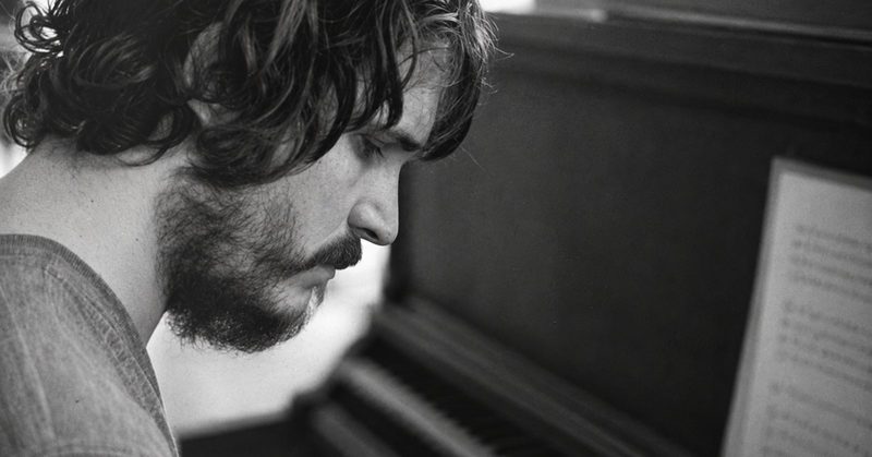 Rafael Anton Irisarri in profile beside a piano, photographed by Sean Curtis Patrick