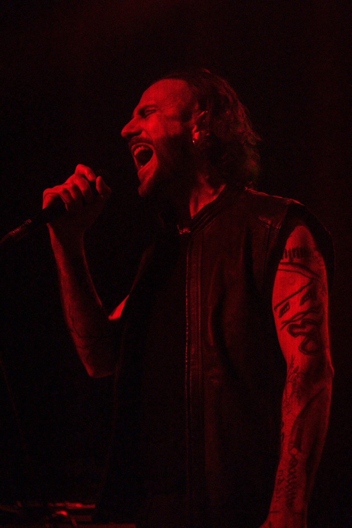 OTTOMAN GRÜW singing into a handheld microphone under red stage light.