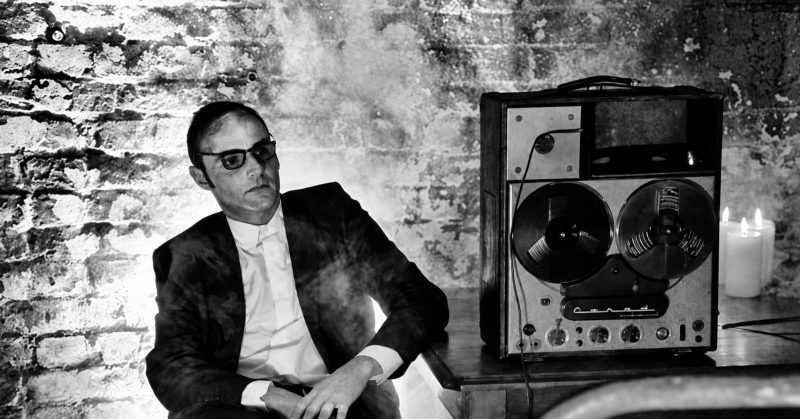 Pepijn Caudron seated beside a reel-to-reel tape recorder in a smoky room
