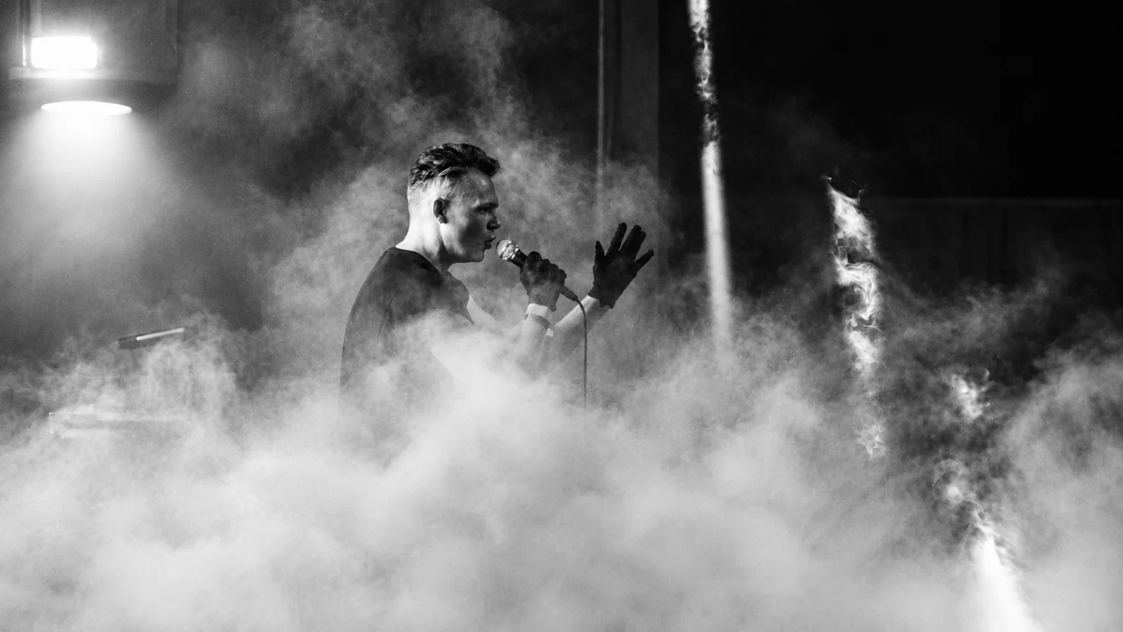 William Maybelline of QUAL performing live amid stage smoke.