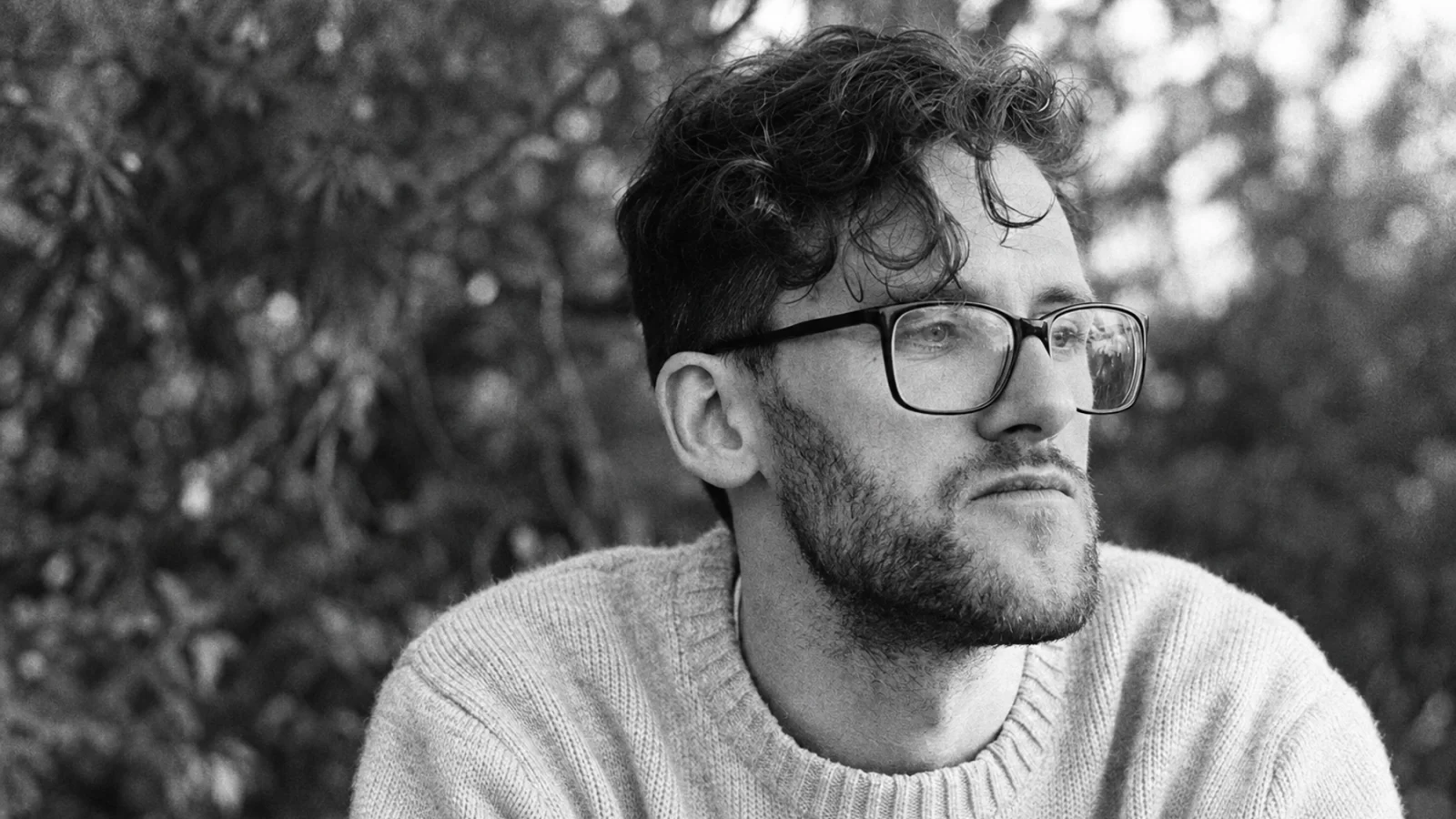 Sraunus outdoors, wearing glasses and a knitted sweater.