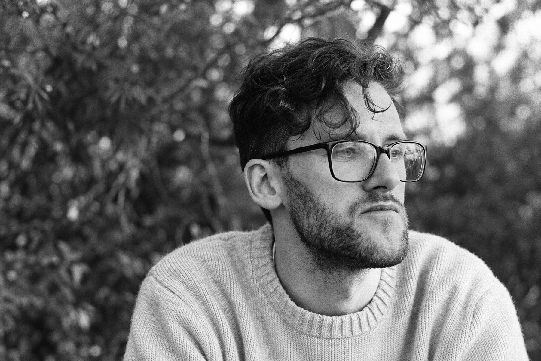 Sraunus outdoors, wearing glasses and a knitted sweater.
