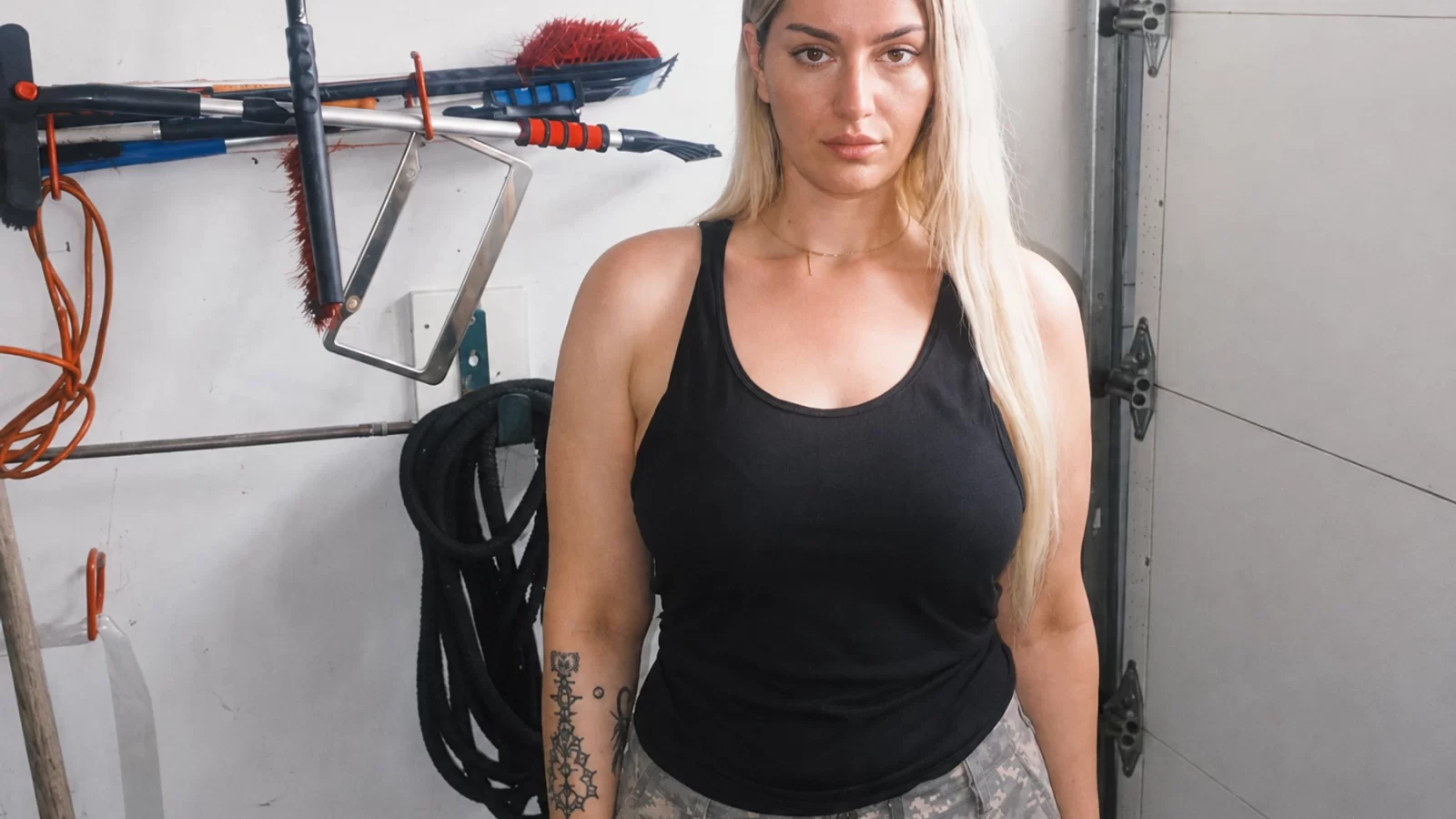 E-Saggila in a black top, standing in a garage.