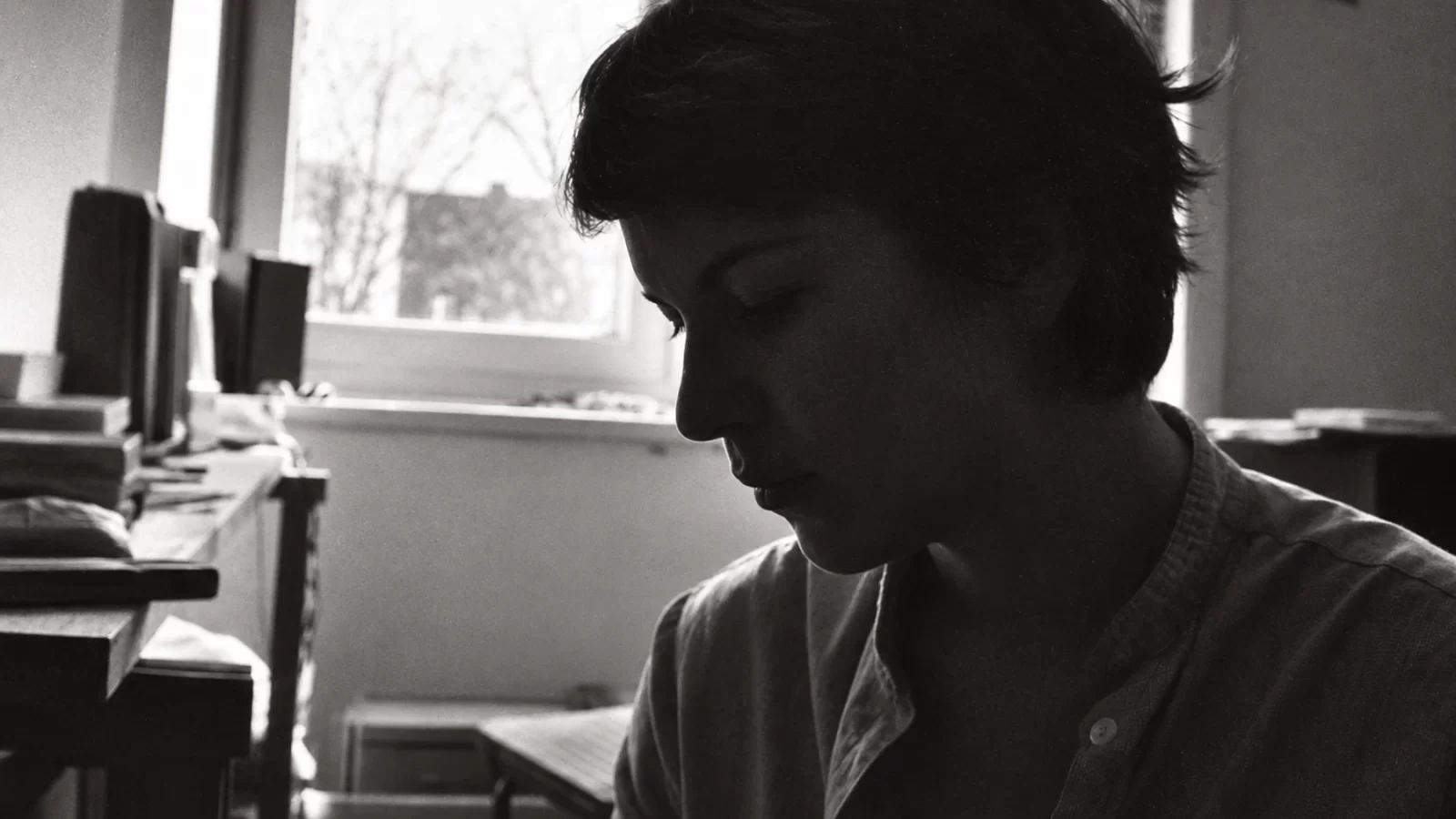 Nina in profile beside a window in a grainy black-and-white photograph.