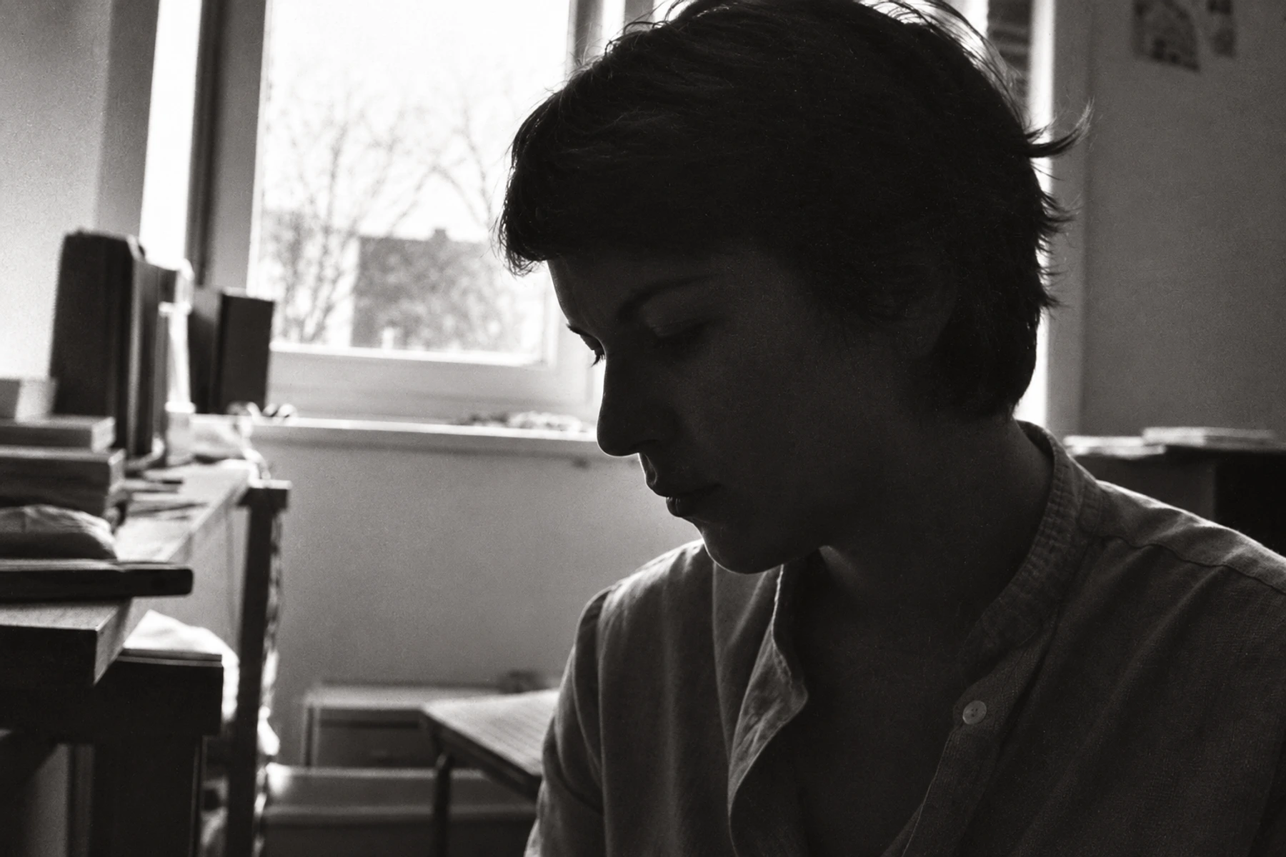 Nina in profile beside a window in a grainy black-and-white photograph.