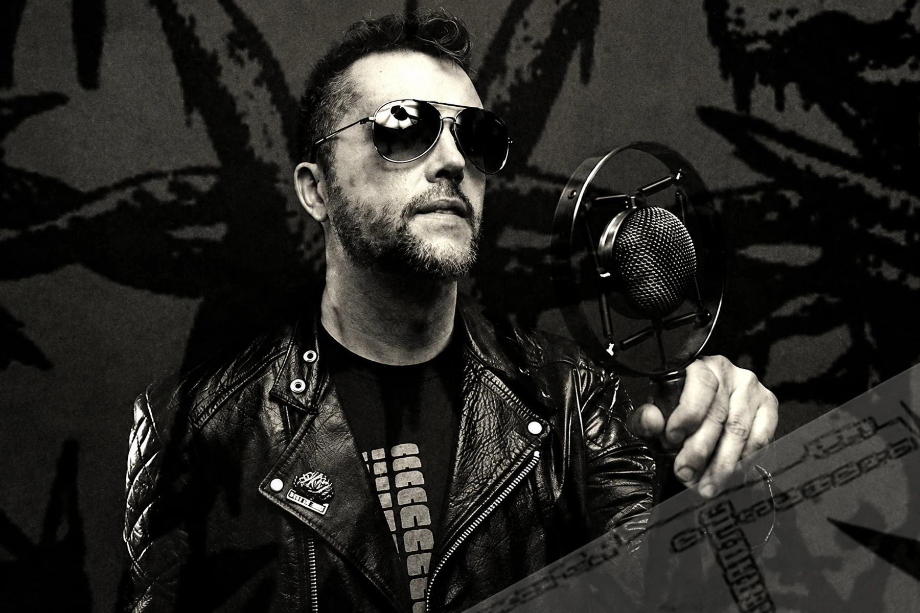 Huren in sunglasses and a leather jacket beside a microphone.
