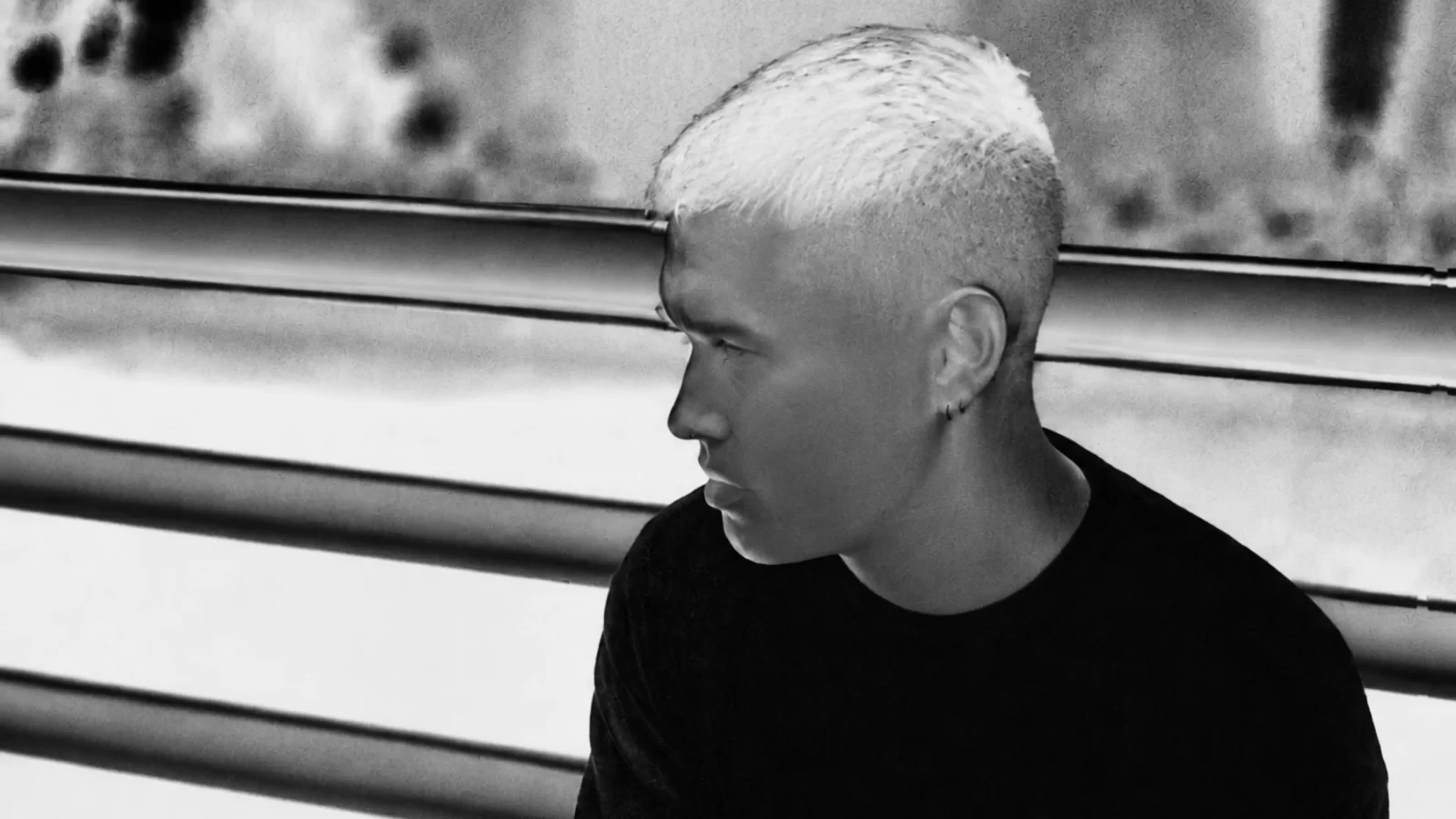 Phase Fatale beside a railing in a black-and-white photographic negative.