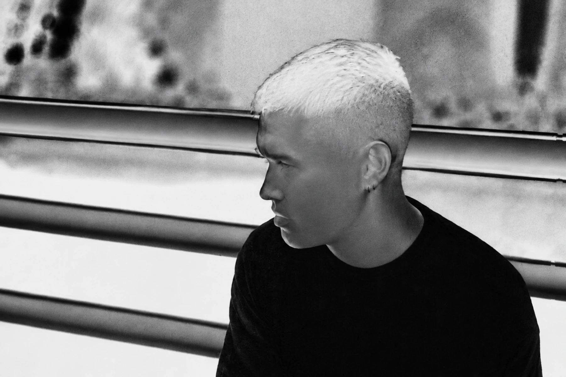 Phase Fatale beside a railing in a black-and-white photographic negative.