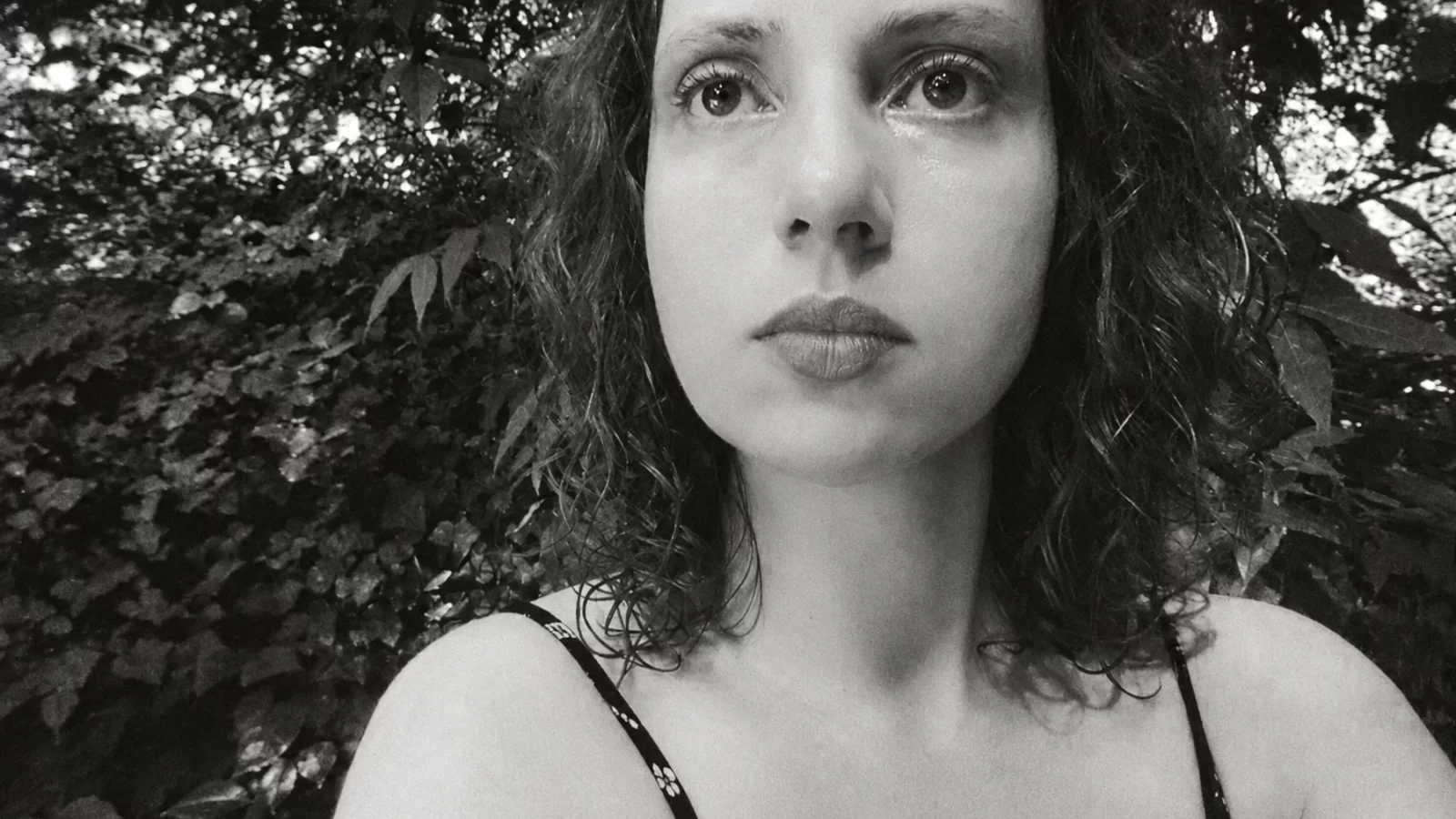 Bérangère Maximin outdoors among foliage in a textured monochrome portrait.