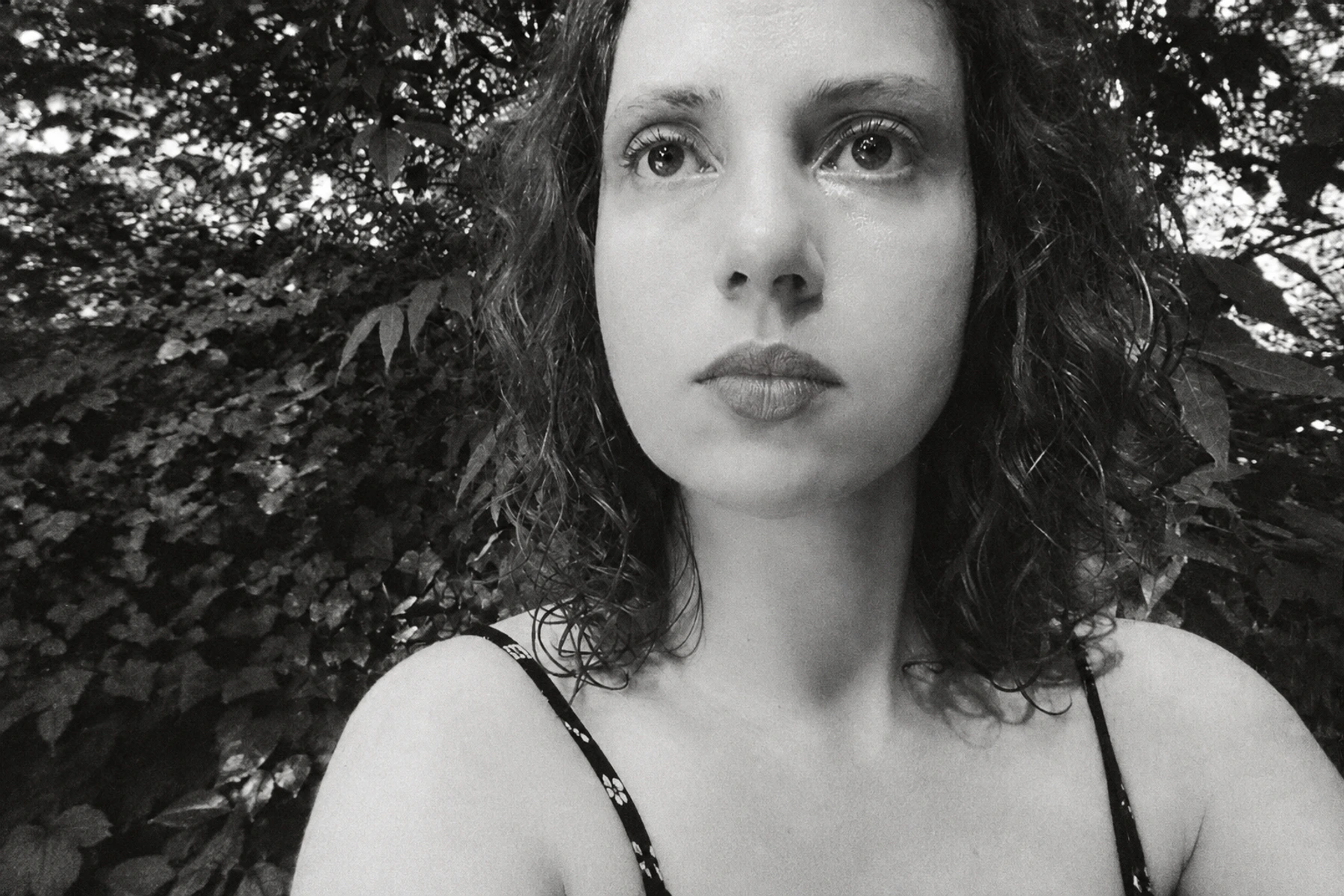 Bérangère Maximin outdoors among foliage in a textured monochrome portrait.
