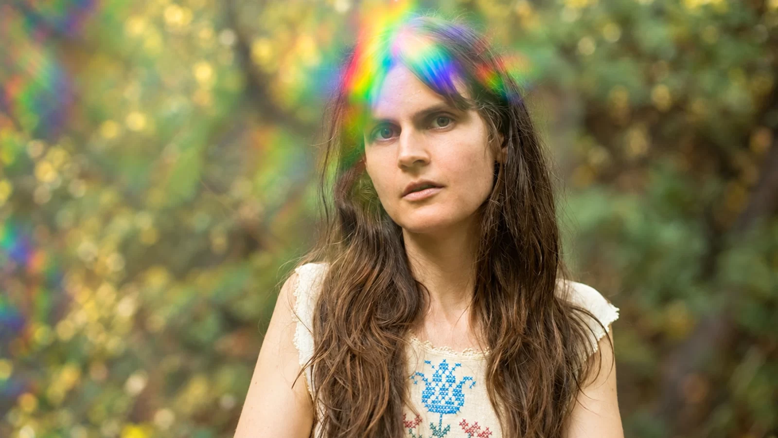 Sarah Louise in a wooded setting with rainbow light across her hair.
