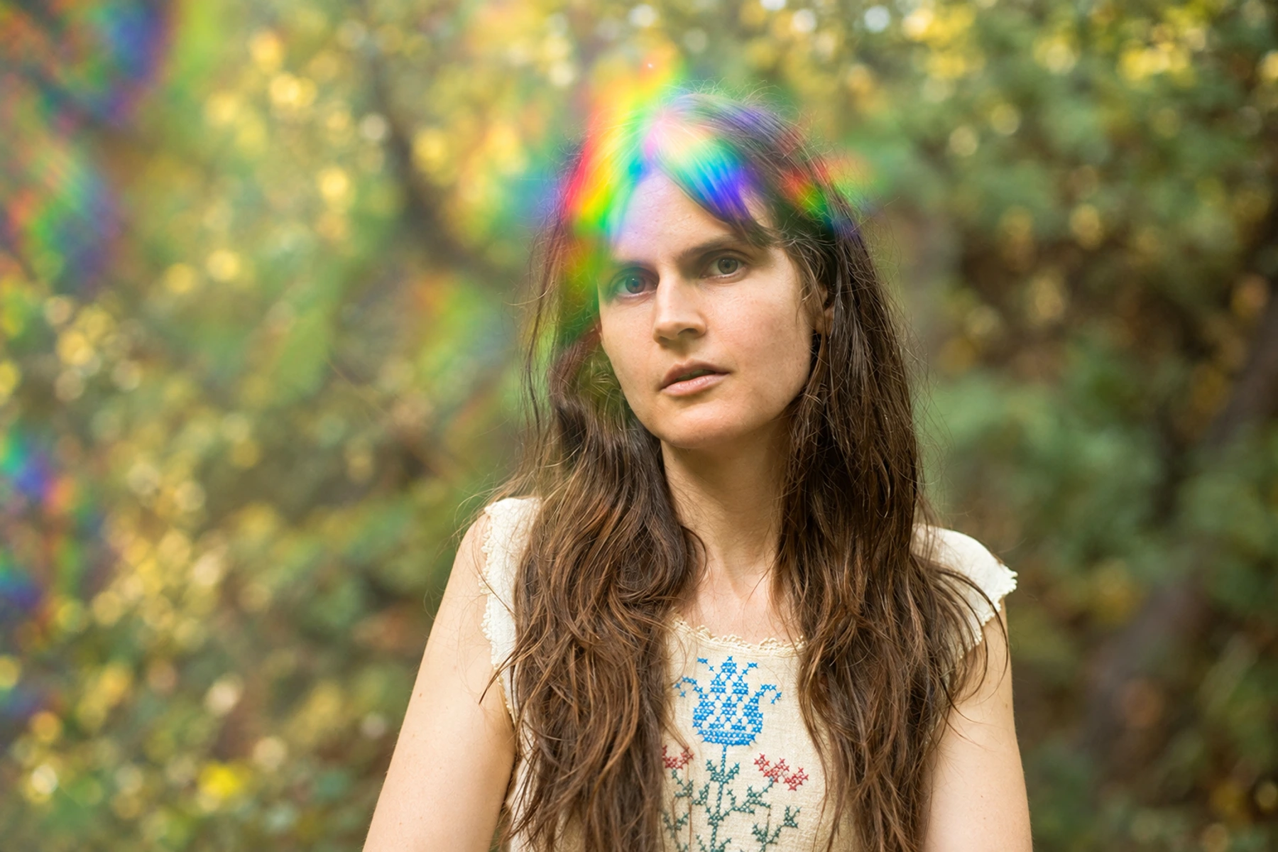 Sarah Louise in a wooded setting with rainbow light across her hair.