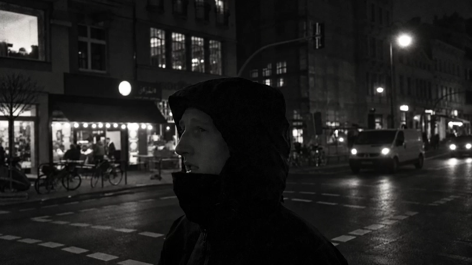 Tourist Gaze in a hooded jacket on a city street at night.