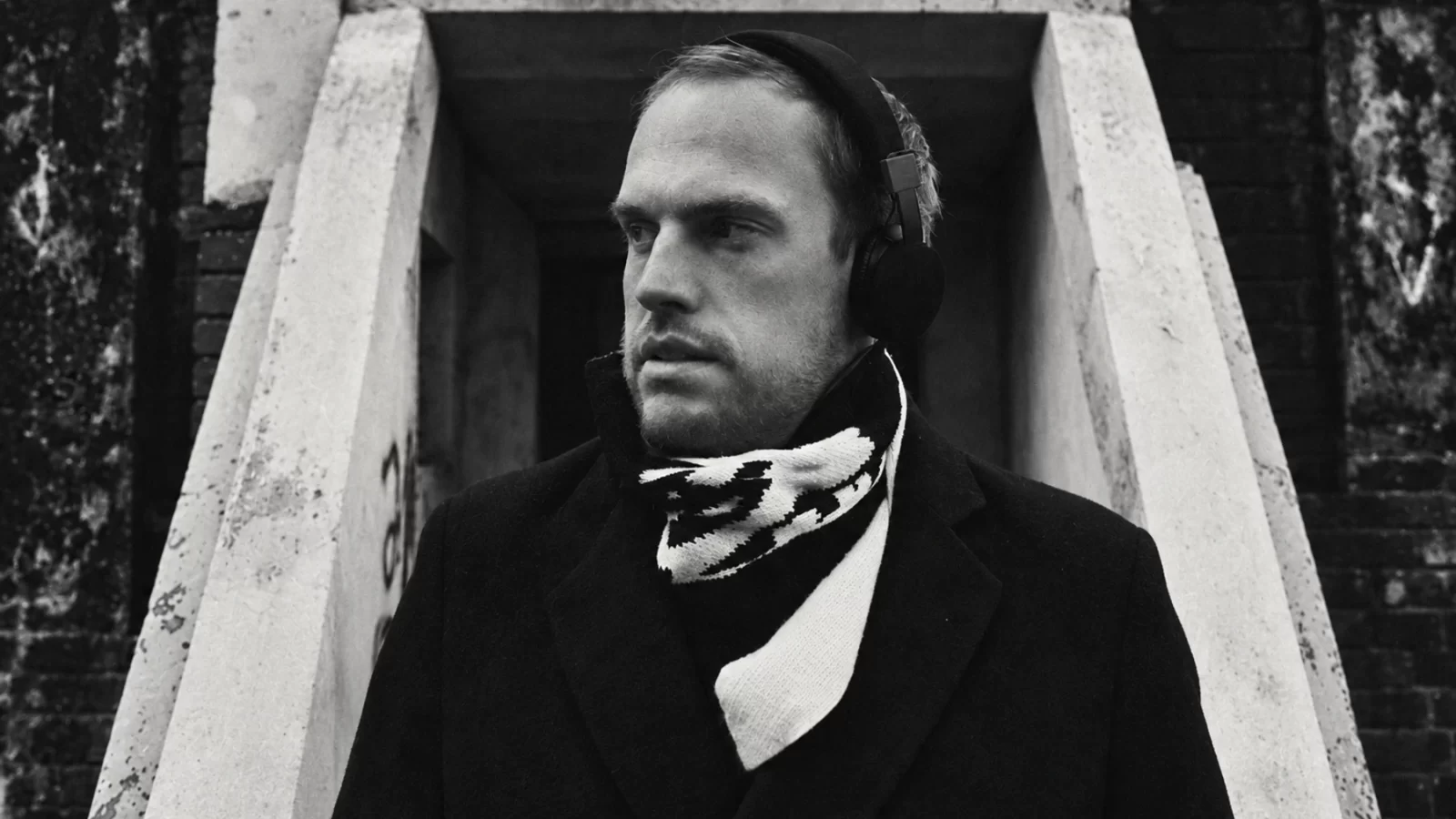 Piotr Podomarof wearing headphones and a patterned scarf in a doorway.