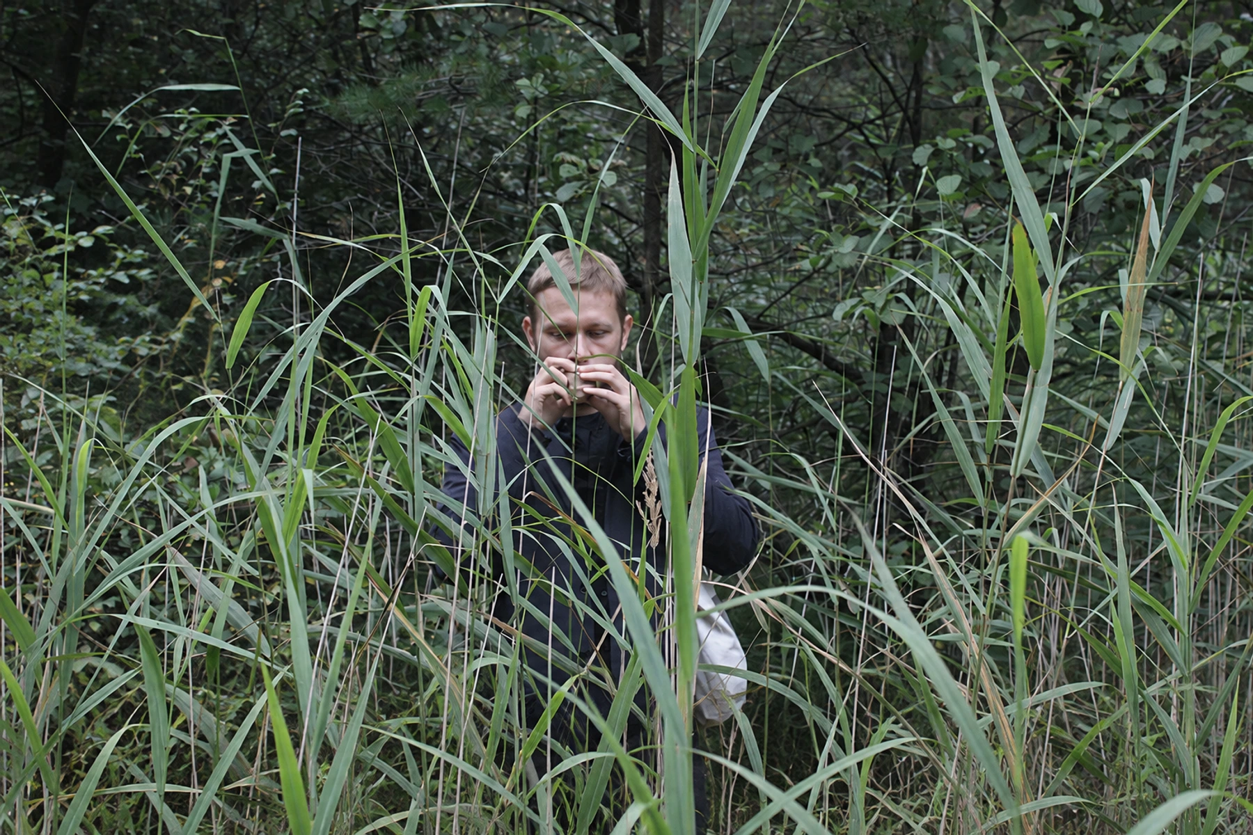 Arturas Bumšteinas playing among tall grasses and trees.