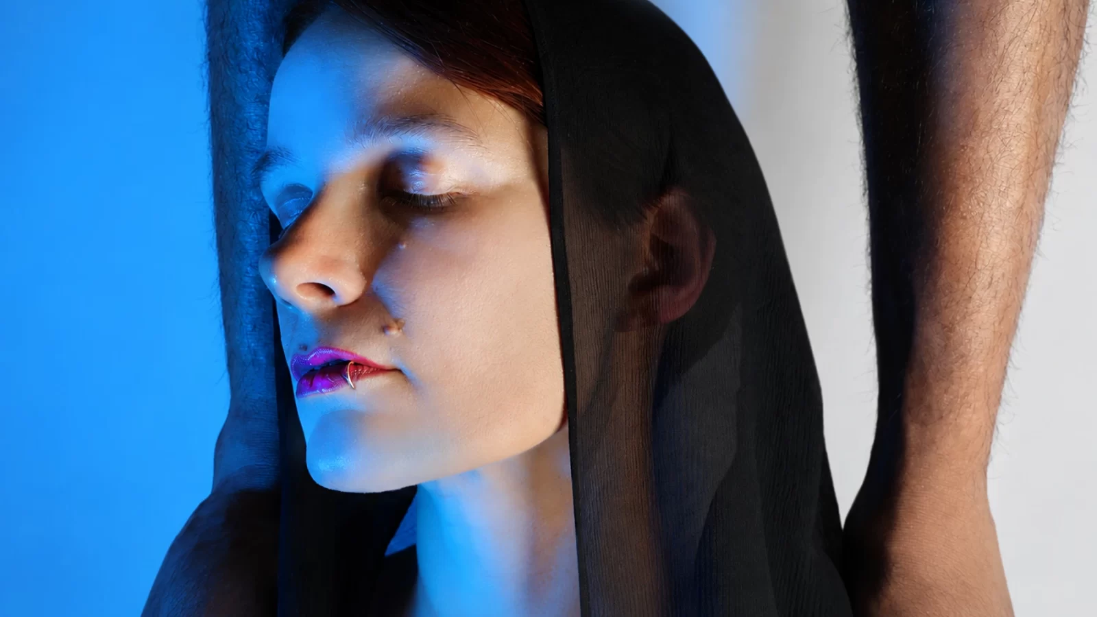 Paco Sala portrait in blue light, with a face behind translucent black fabric.