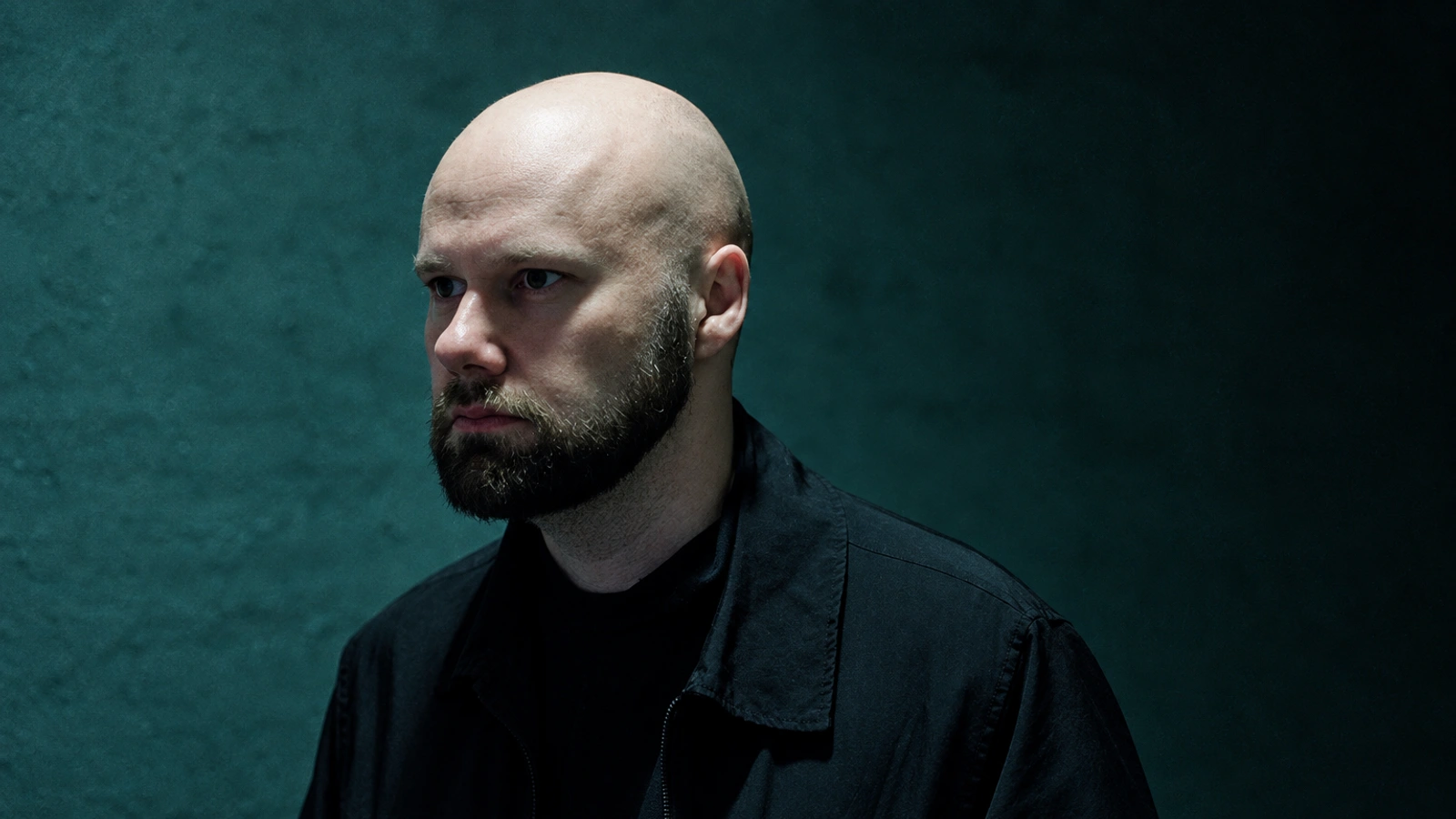 Lasse Marhaug in a dark shirt against a muted blue-green wall.