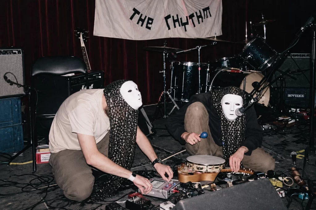 The wider High Wolf archival scene with masked figures and patterned fabric.