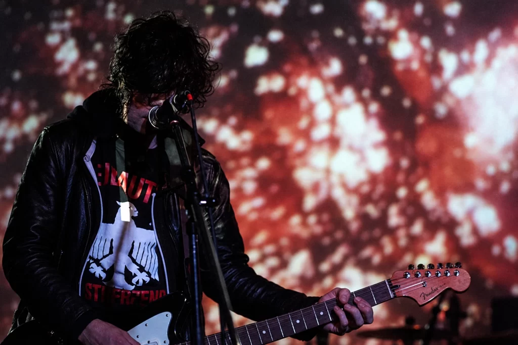 The KVB performing with guitars beneath red projected light.
