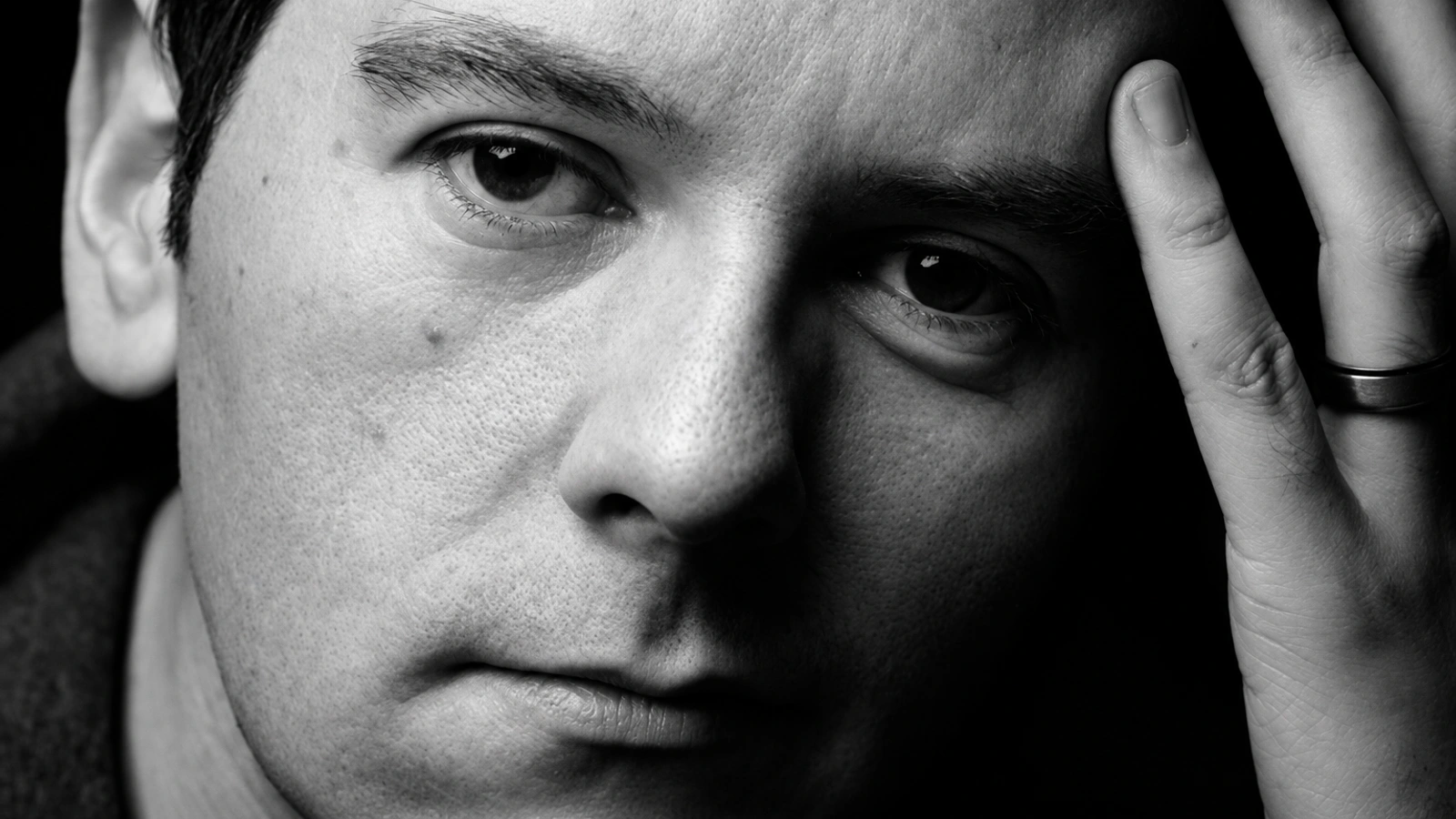 ASC in the iconic monochrome close-up portrait with his hand resting against his temple.