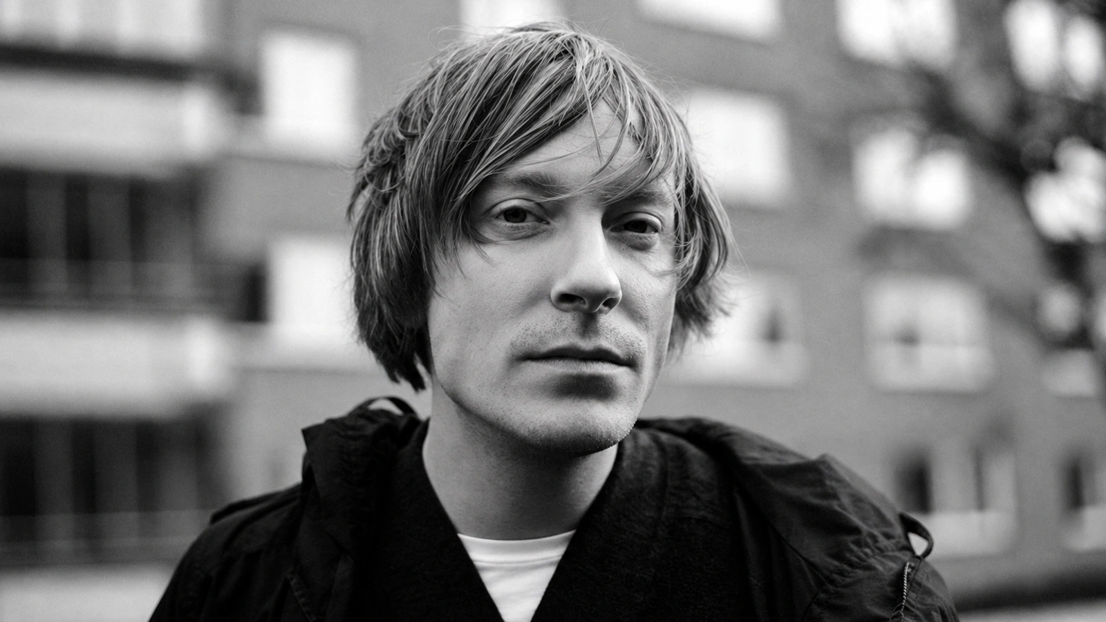 Andreas Tilliander, known as Mokira, in a textured monochrome close portrait against an out-of-focus urban background.