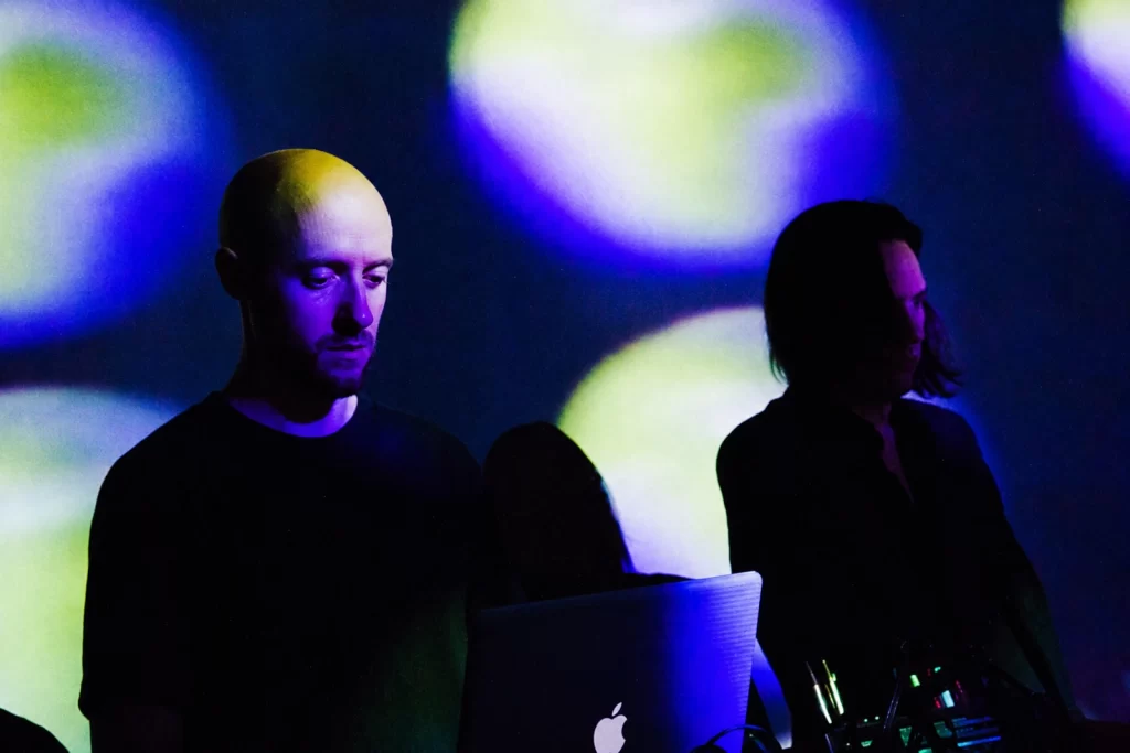 Team Doyobi performing under violet, blue and green projections.