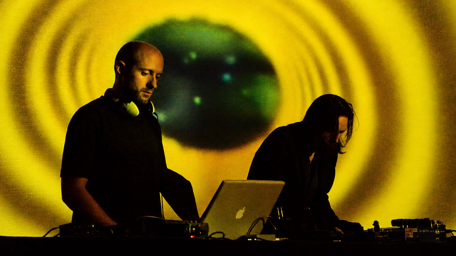 Team Doyobi performing beneath yellow and green circular projections, with a laptop and electronic instruments.