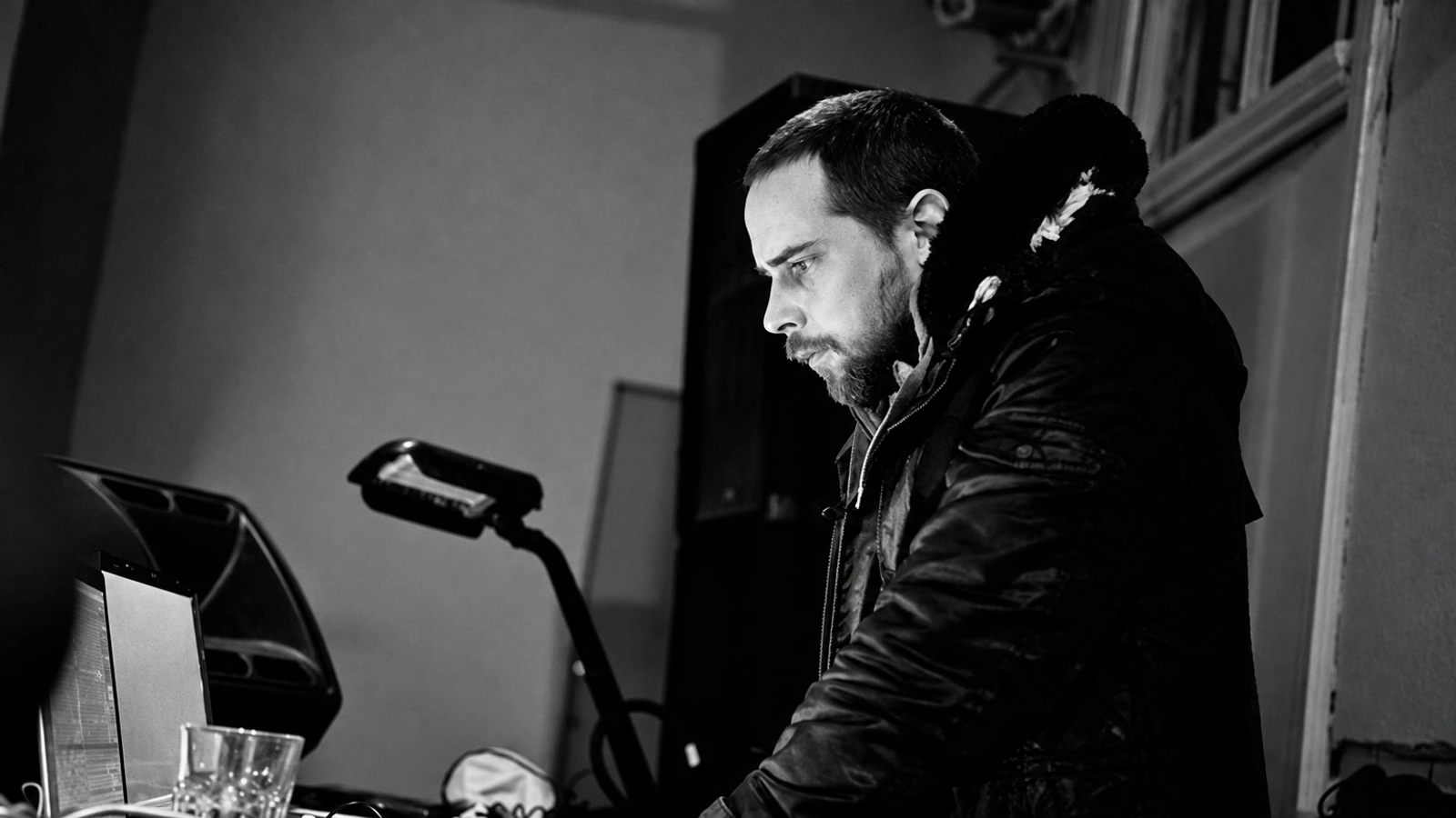 Grischa Lichtenberger performing at a table of electronic equipment, in a textured monochrome photograph.
