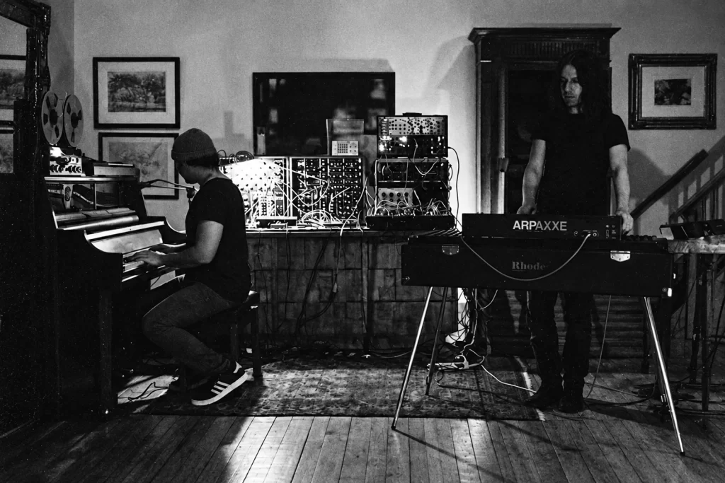 Locust in the studio, with piano, keyboards and a modular synthesizer between the two musicians.