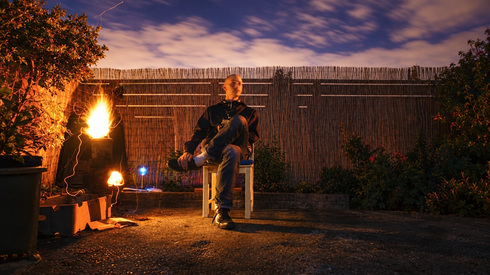 Conor Thomas seated outdoors at night beside warm lights, beneath a purple clouded sky.