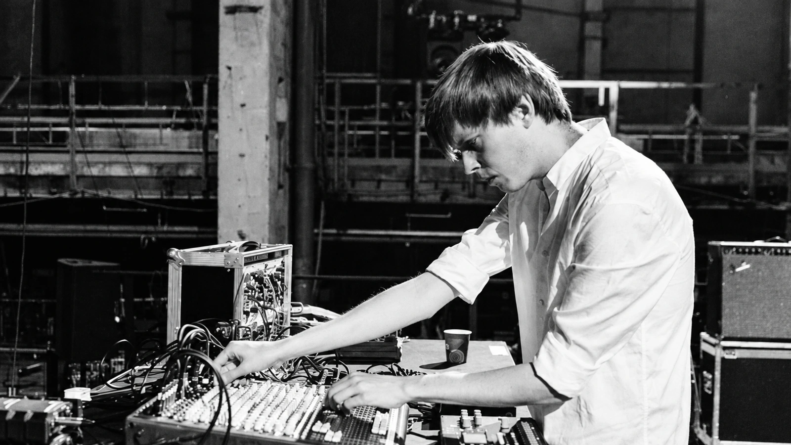 Helm performing with a mixer and electronic instruments in an industrial interior.