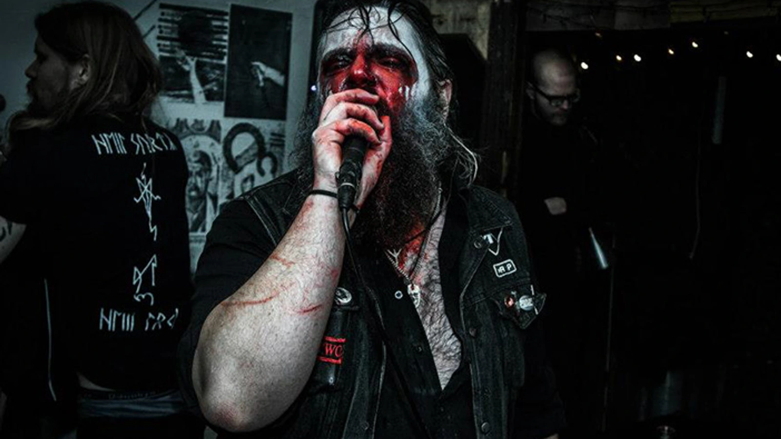 Trepaneringsritualen performing with a microphone, face paint and a black leather vest.
