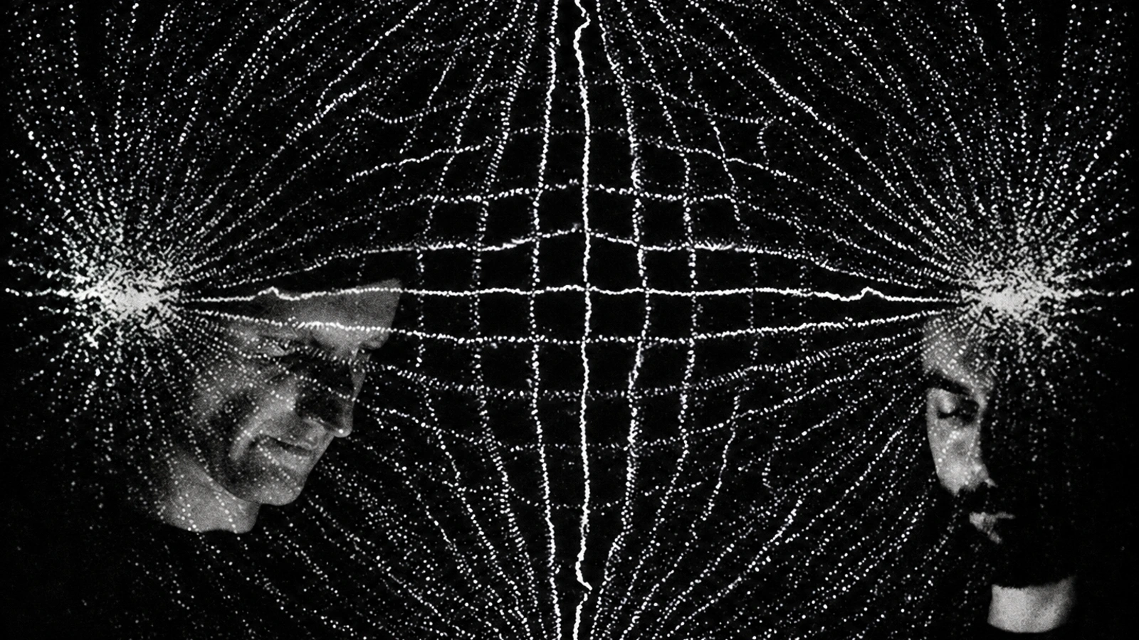 Dadub in a dark monochrome portrait, with geometric light patterns projected over both members.
