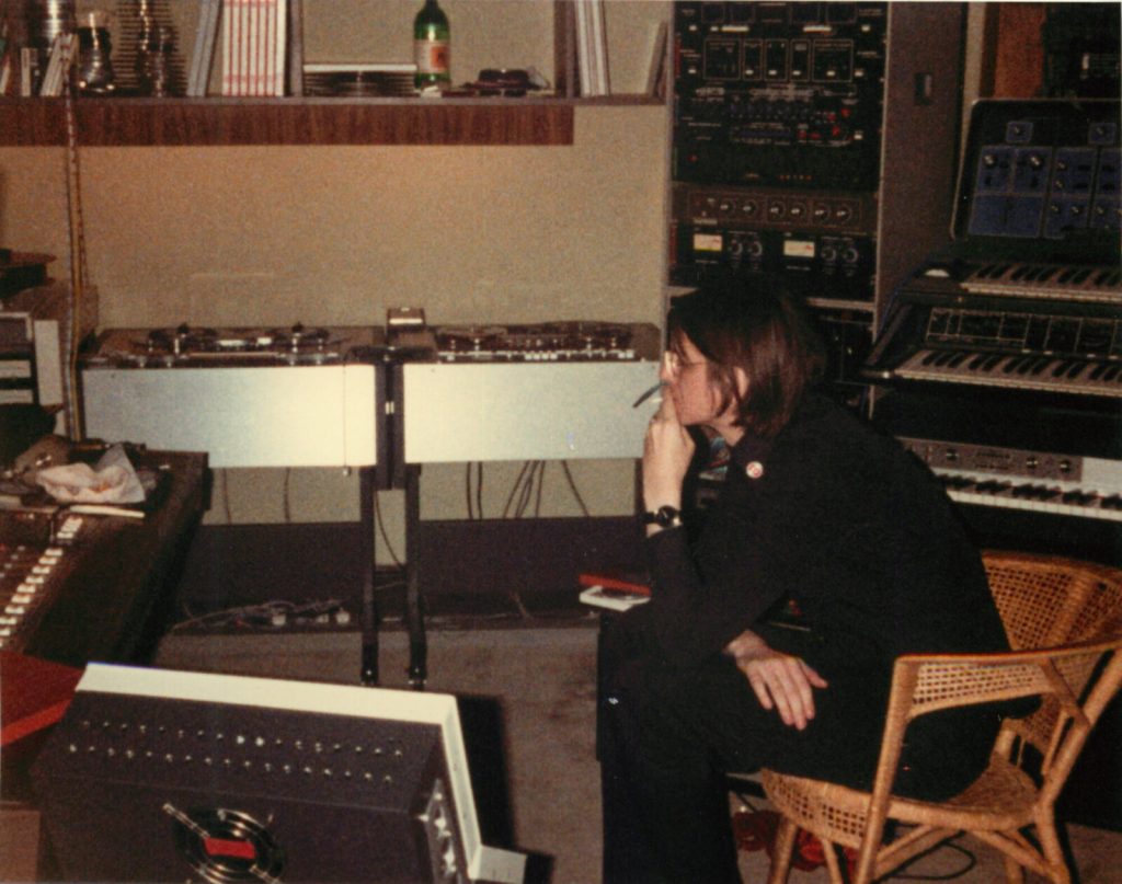 Asmus Tietchens seated among tape machines and synthesizers in his studio in 1980.