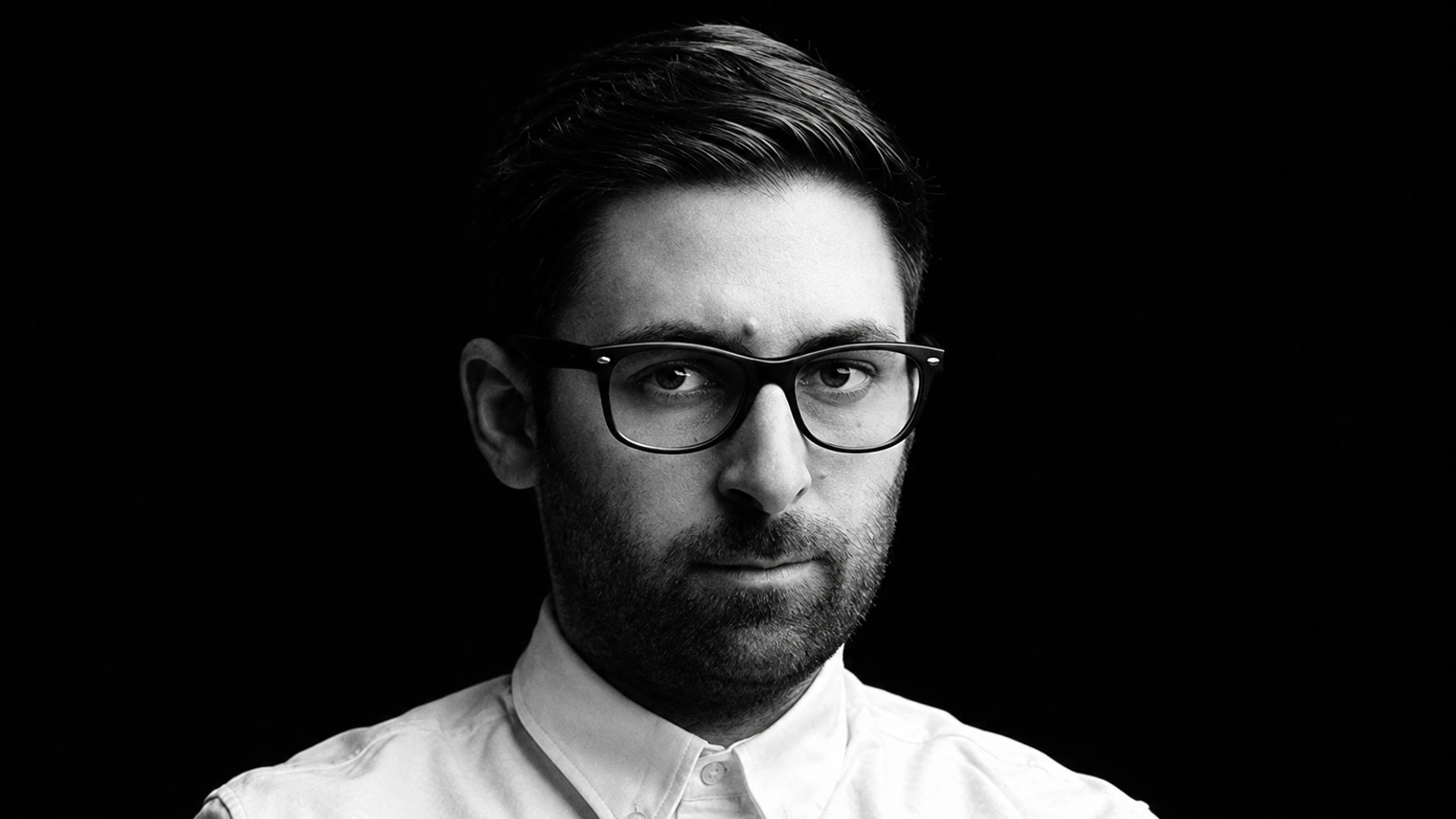 Close-up black-and-white portrait of Cosmin TRG in glasses and a white shirt.