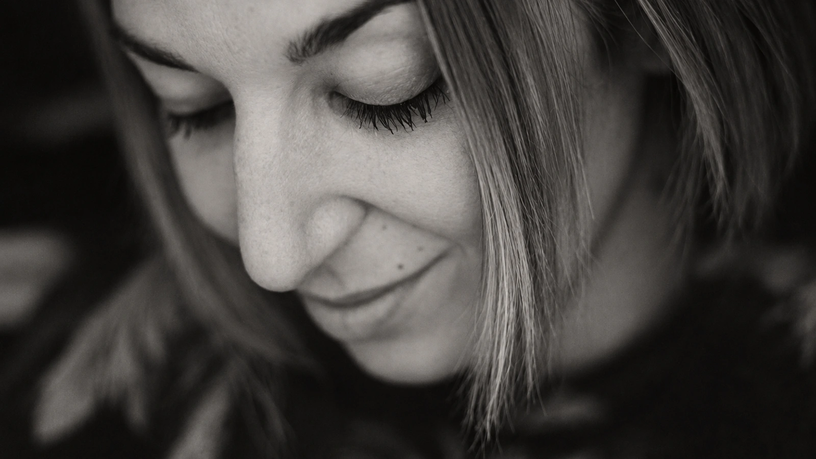 Mira Calix with her eyes closed and a slight smile in an intimate black-and-white portrait.