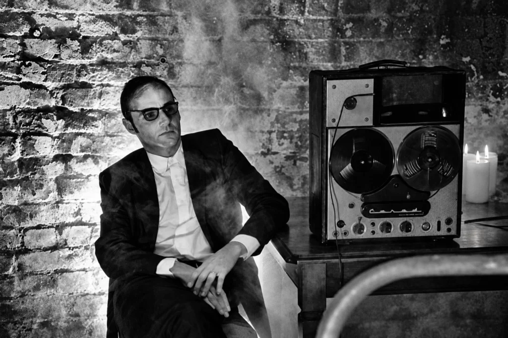 Pepijn Caudron sitting beside a reel-to-reel recorder against a brick wall, with candles and smoke.