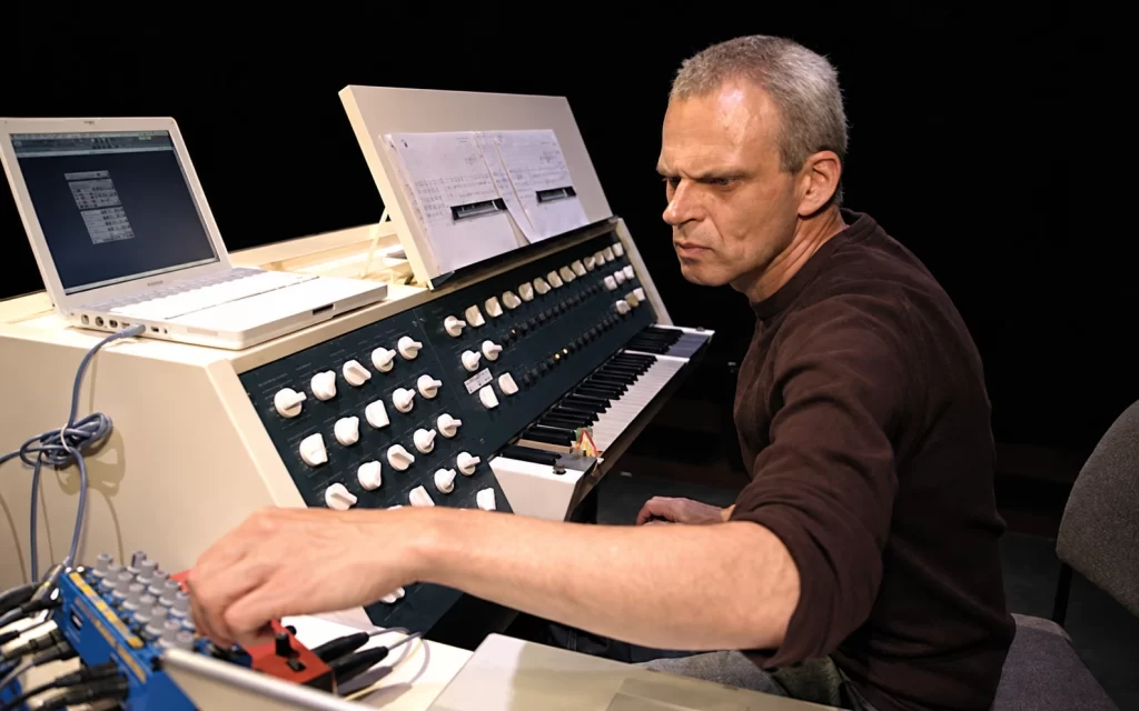 Frank Bretschneider working at a synthesizer with a laptop and a printed score.