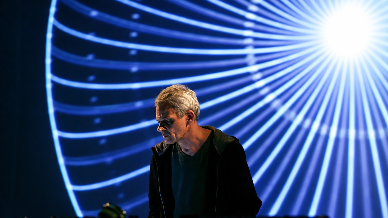 Frank Bretschneider performing in front of radiating blue projected lines.