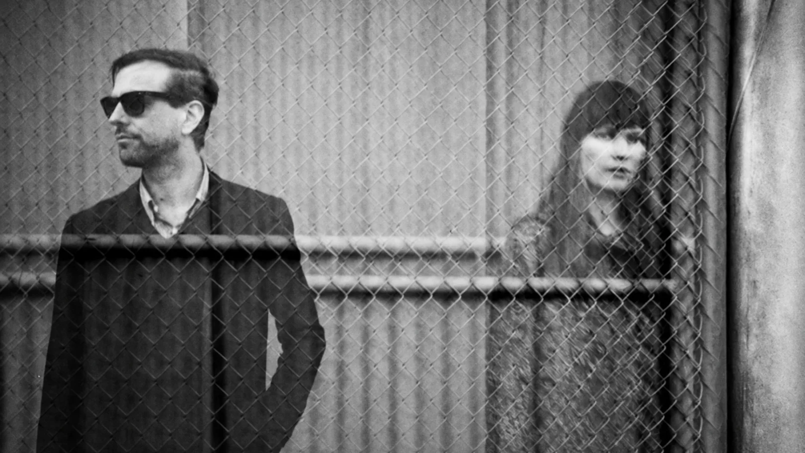 Xeno & Oaklander seen through a chain-link fence in a ghostlike double-exposure photograph.