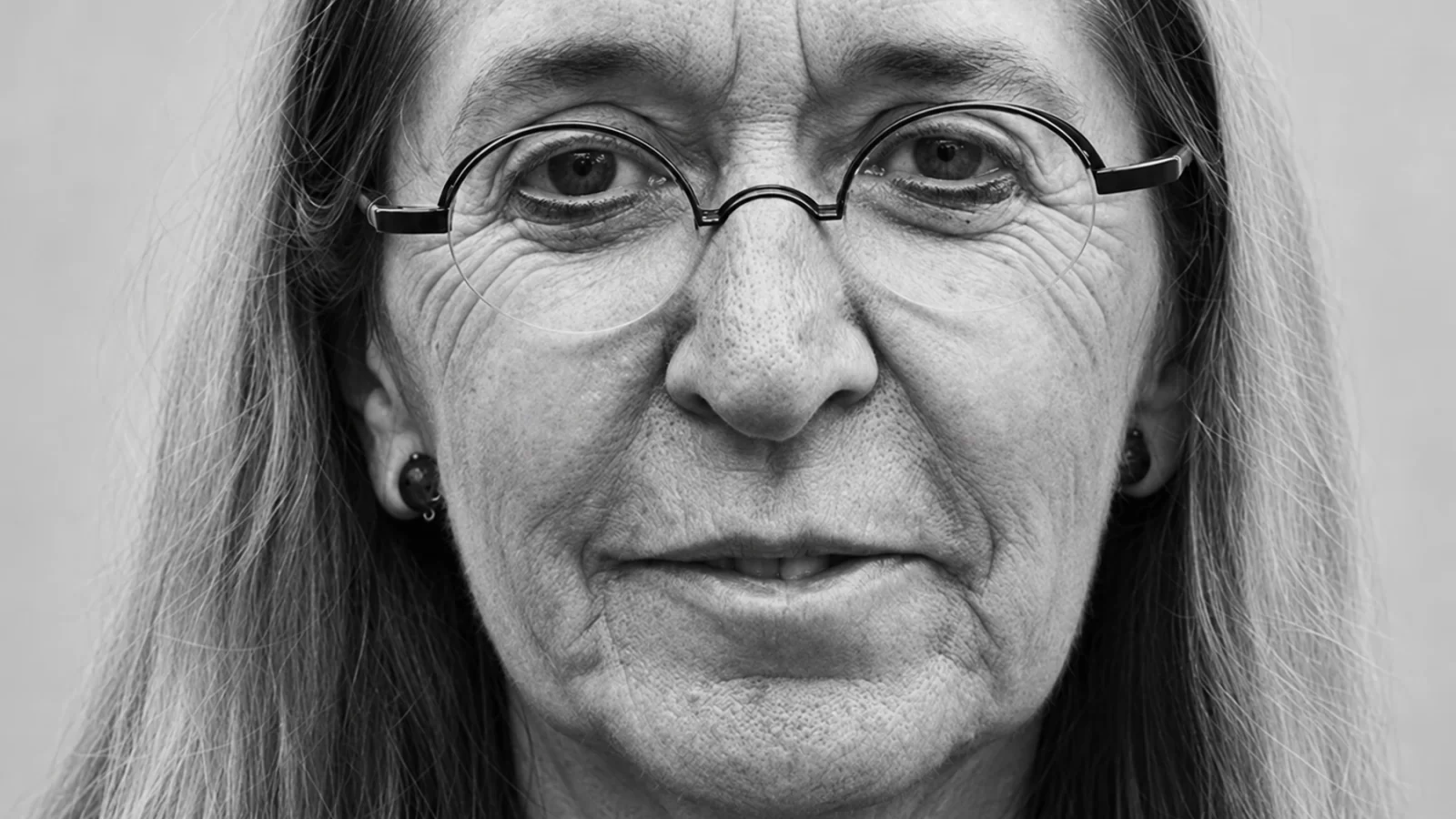 Close-up black-and-white portrait of Moniek Darge wearing round glasses.
