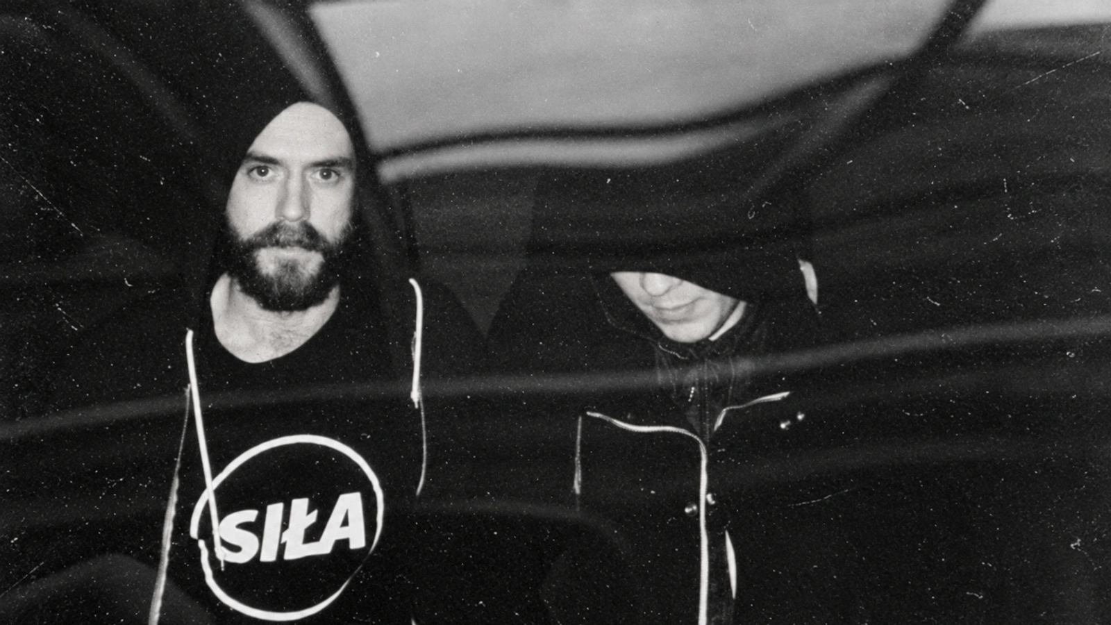 AnD in black hoodies, photographed through a grainy reflective surface.