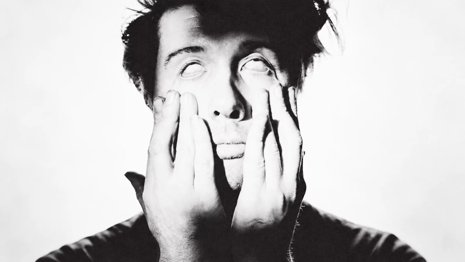Buzz Kull in a stark black-and-white portrait, holding his face.