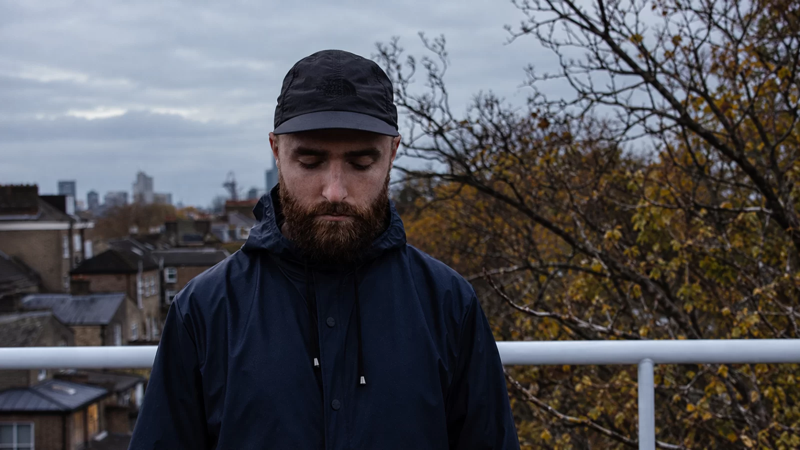 Asher Levitas outdoors, looking down in front of a city skyline.