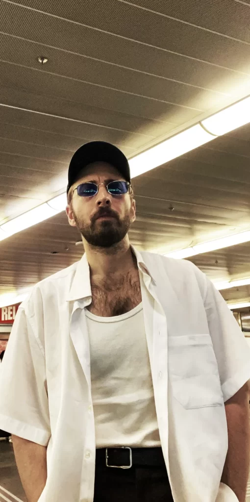 Sean Piñeiro, known as Emra Grid, wearing a white shirt beneath a fluorescent light