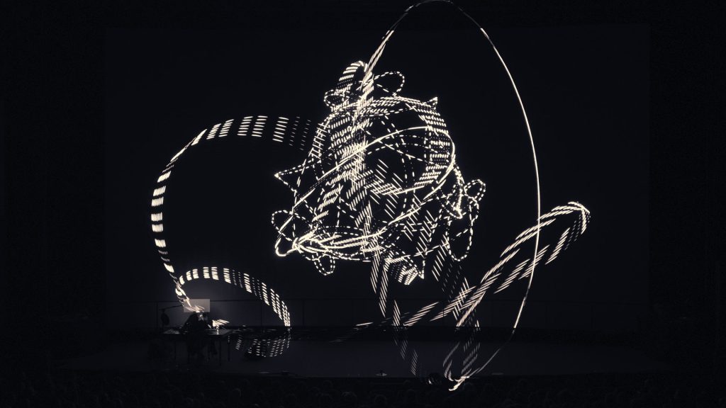 A geometric laser projection above Robert Henke at the premiere of Lumière I at Unsound in 2013