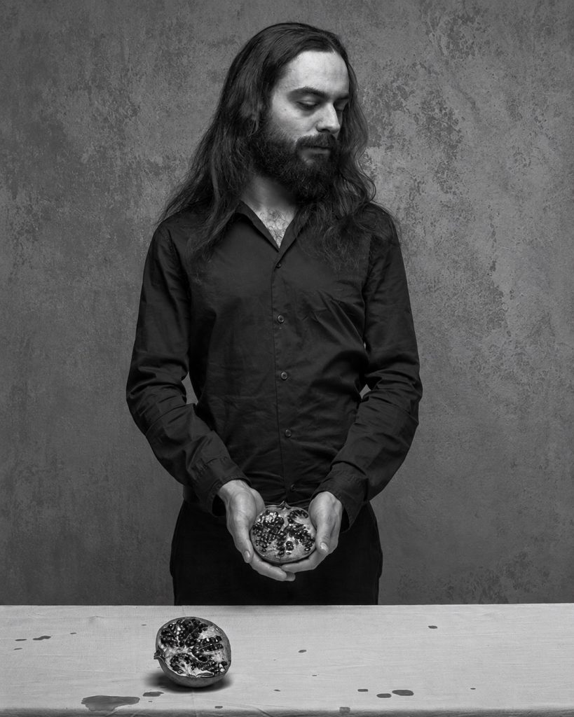 Daniele Antezza holding a pomegranate in a Berlin portrait